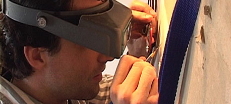 Billy Pappas using 20-powered magnification to work within a space the size of a period in the newspaper.